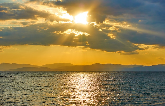 海に沈む夕日と地平線に山のある土地-パノラマの夕日の海風、風景