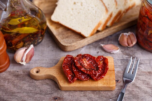 Foto tomati secchi all'olio d'oliva su una mini tavola con pane fatto in casa in stile rustico cucina casalinga tradizionale close-up selettivo