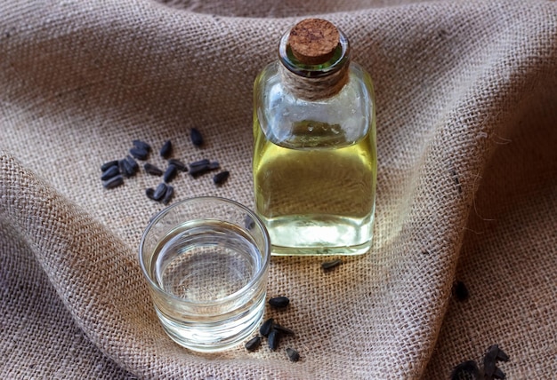 Sunflower oil in a bottle glass with seeds on burlap canvas fabric background