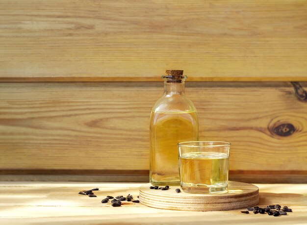 Sunflower oil in a bottle glass with seeds on wooden background