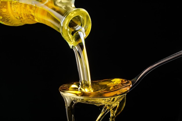 sunflower oil is poured into a spoon on a dark background closeup