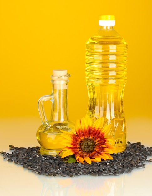 Sunflower oil in a plastic bottle and small decanter on yellow