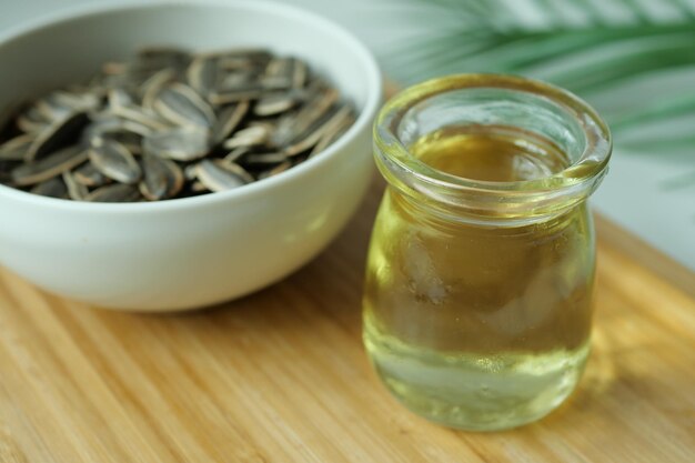 Семена подсолнечного масла и масло в контейнере на столе
