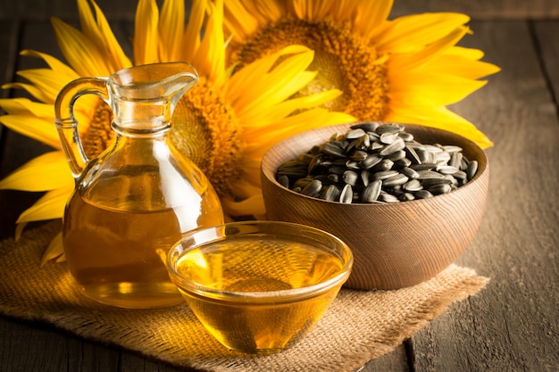 Sunflower oil with seeds on wooden background. 