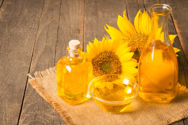 Photo sunflower oil with seeds on wooden background