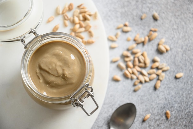 Sunflower seeds butter in glass jar on gray background