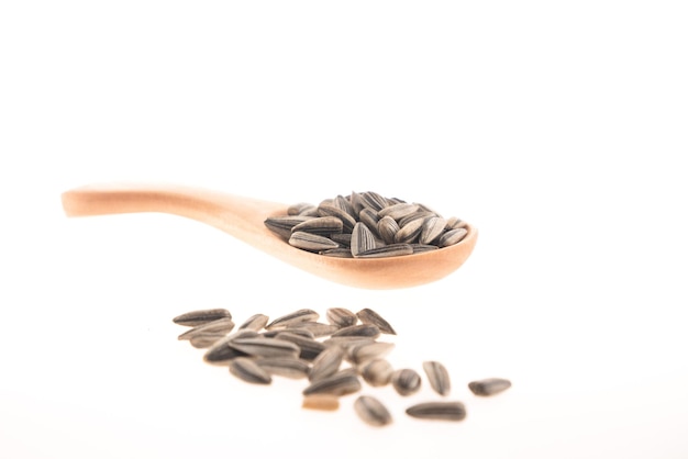 Sunflower seeds in a wooden spoon, isolated on a white background