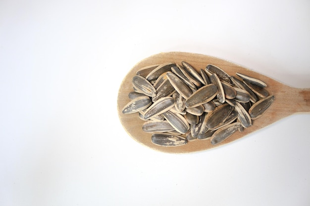 Sunflower seeds in wooden spoon over white background