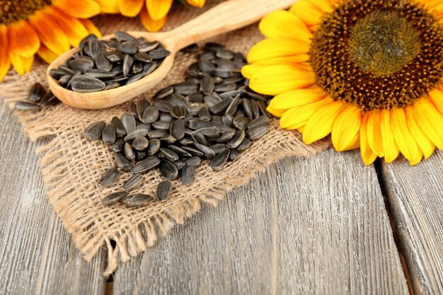 Sunflowers and seeds with spoon on wooden background