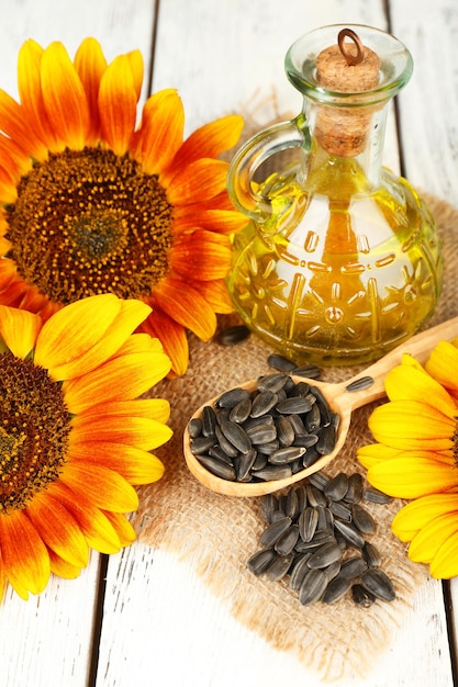 Sunflowers with oil and seeds on wooden background