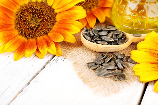 Sunflowers with oil and seeds on wooden background