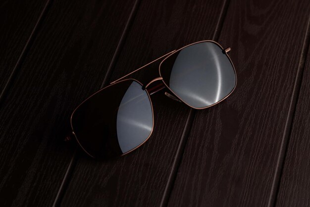 Sunglass on brown textured wood table with dark background