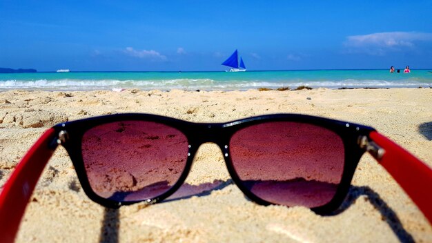 Photo sunglasses on beach against sky on sunny day
