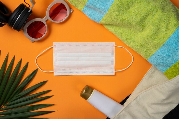 Sunglasses, facemask and beach objects on orange summer beach background