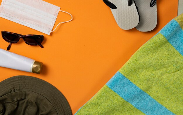 Sunglasses, facemask and beach objects on orange summer beach background