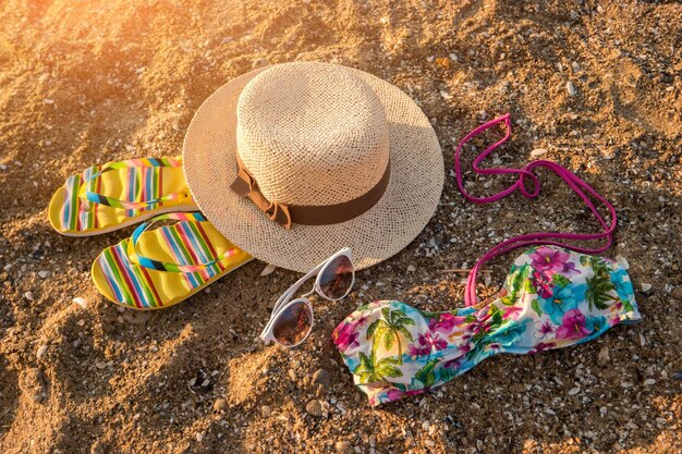 Солнцезащитные очки и шляпа на песочном красочном купальнике встречают лето, идут купаться
