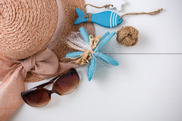 Sunglasses, hat and summer accessories on white wood background