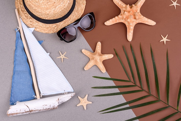 sunglasses and hat with shells and sea stars on a colored surface