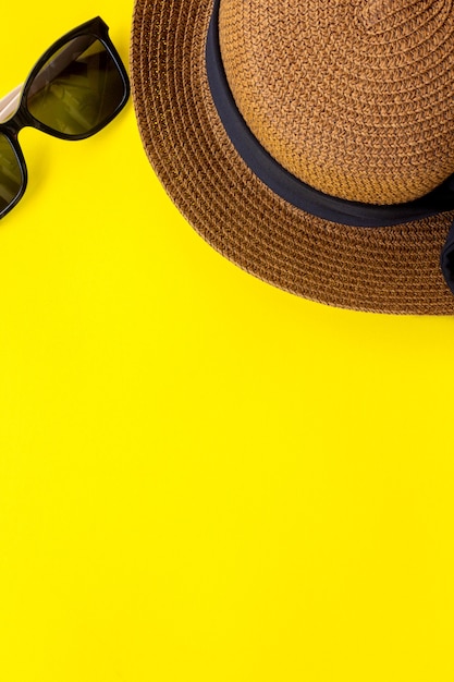 Sunglasses and hat on yellow background