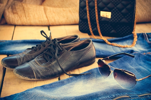 Sunglasses, jeans, handbag and old shoes. Toned image.