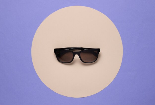 Sunglasses on purple background with yellow pastel circle. Top view