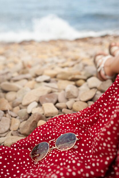 Sunglasses on red fabric from dress on rocky beach