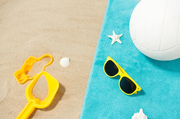 sunglasses sand toys and ball on beach towel