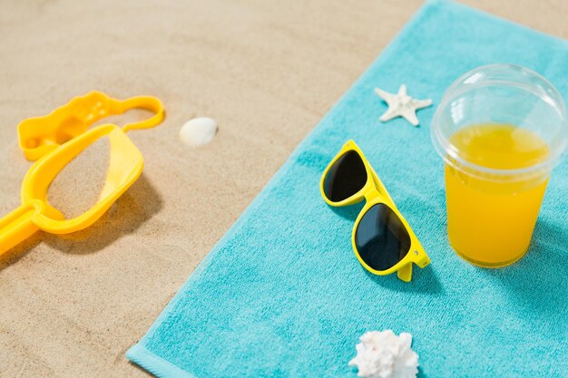 sunglasses sand toys and juice on beach towel