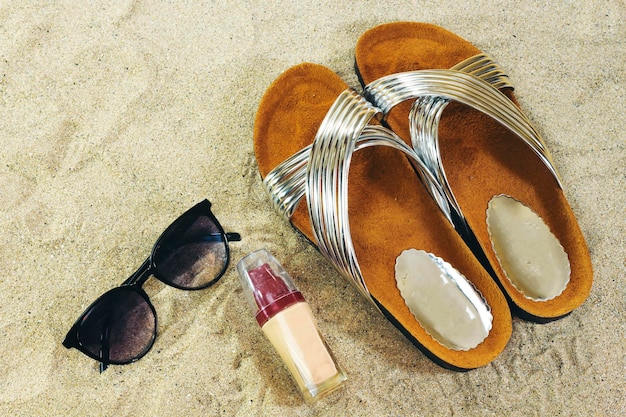 Sunglasses and slippers liquid foundation on sand summer concept