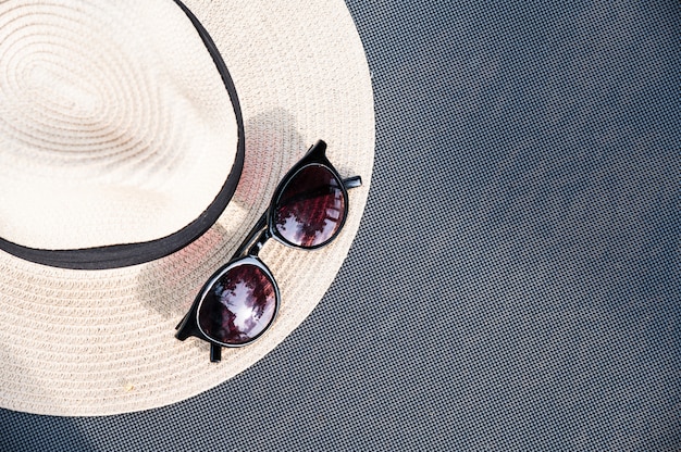 Sunglasses and straw hat on the beach bed