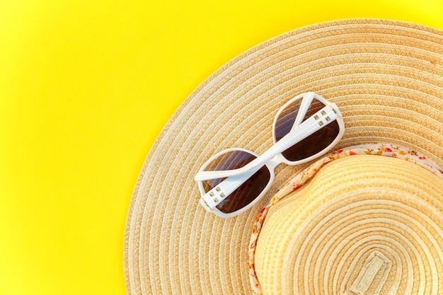 Sunglasses and striped retro hat on yellow background