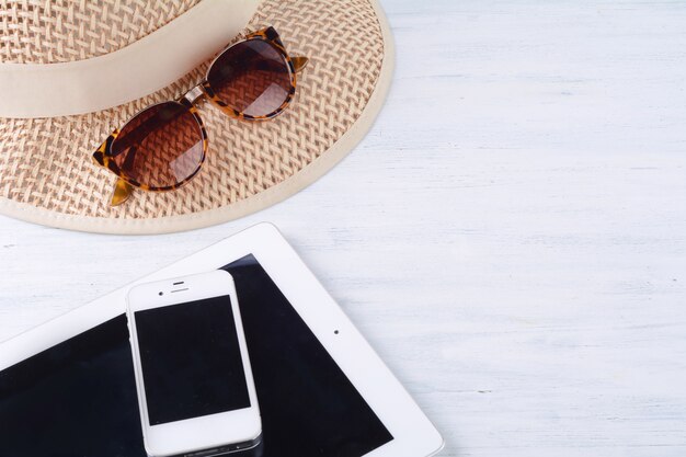 Sunglasses with a hat, digital tablet and a smartphone.