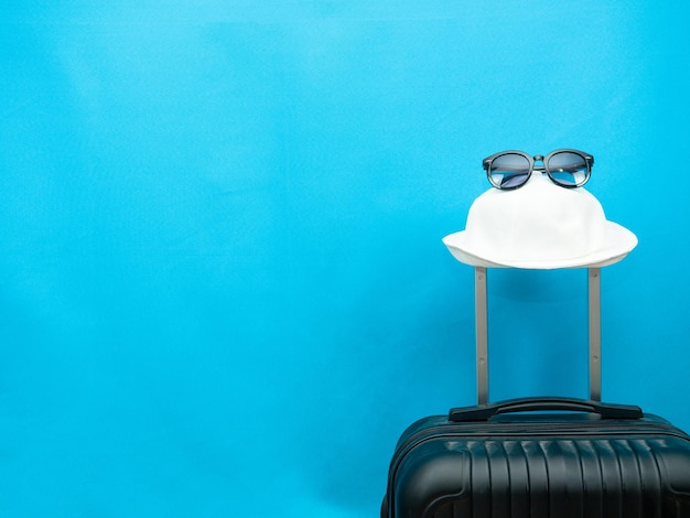 Foto occhiali da sole con cappello sullo spazio della copia del fondo blu dei bagagli