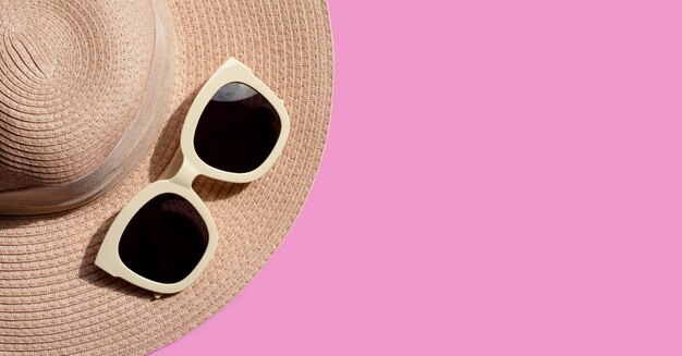 Occhiali da sole con cappello estivo su sfondo rosa. goditi il concetto di vacanza.