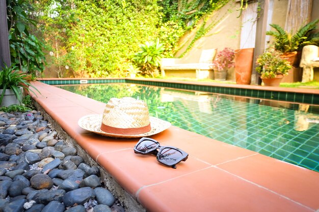 Photo sunglasses with vintage straw hat fasion on swimming pool