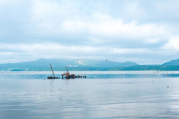 Sunken ship against the backdrop of a sea bay with foggy mountains in the background