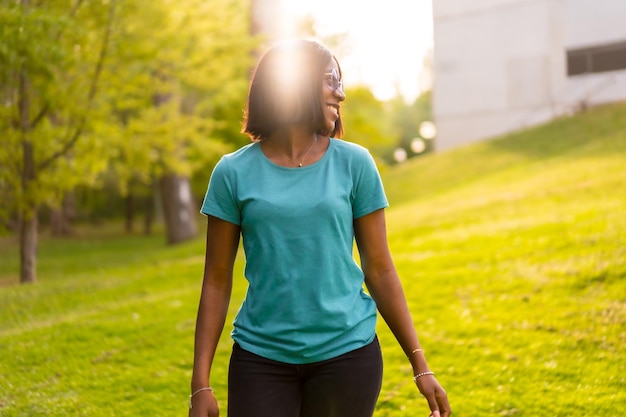 Sunkissed Adventure Portrait of an African American Female Tourist with Green Shirt and Sunglasses Enjoying the Outdoors at Sunset