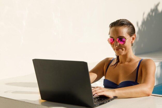 Photo sunkissed productivity stylish girl with laptop in pool