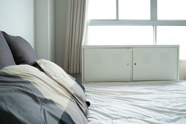 Фото Солнечный свет постельное бельё с чистыми белыми подушками и кроватью в спальне.