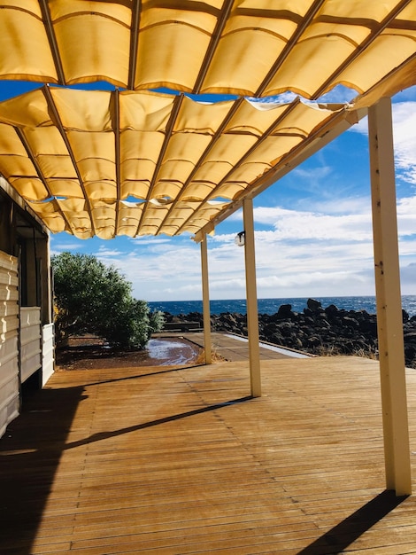 Sunlight falling on wooden floor by sea against sky