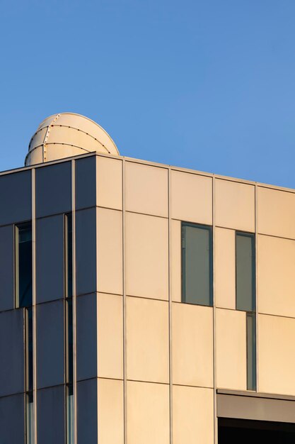 Riflessione della luce solare sulla superficie della parete dell'edificio moderno con camino di ventilazione contro il cielo blu