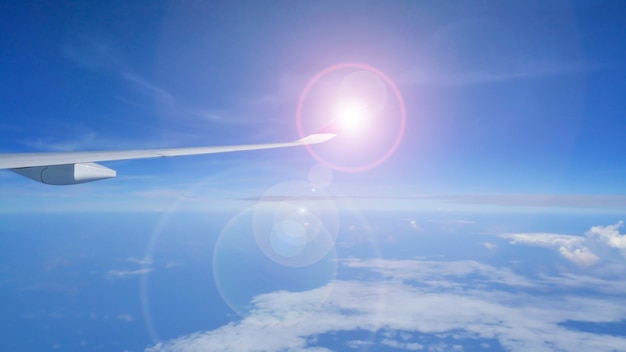 Sunlight reflects on the wings of a passenger plane while flying in the sky.