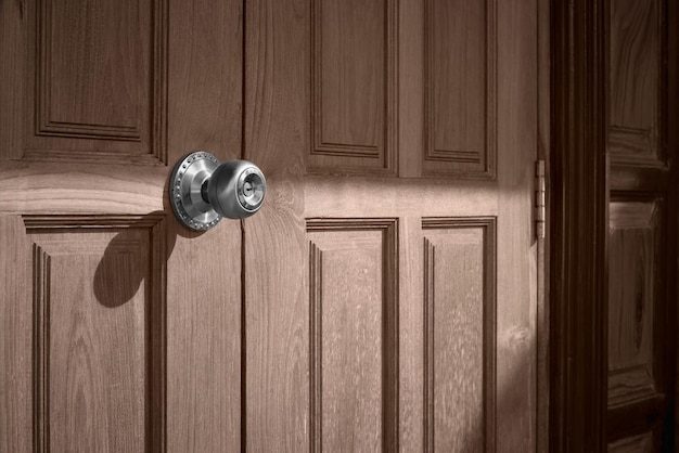 Sunlight and shadow on surface of doorknob on teak wood door in vintage tone style