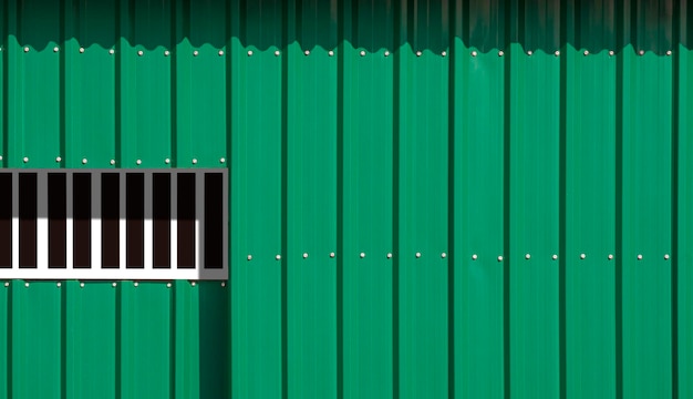 Sunlight and shadow on surface of sliding entrance door on green corrugated steel wall background