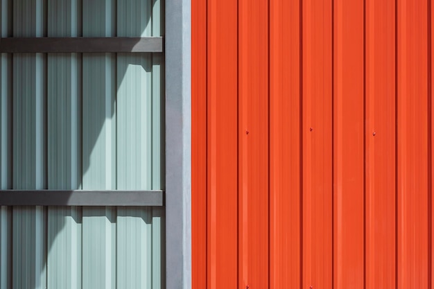 Солнечный свет на поверхности стальной стены складского помещения с оранжевой стеной из металлического листа снаружи дома