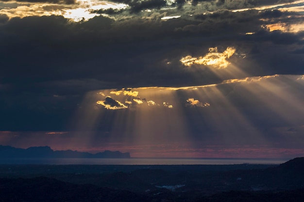 Foto la luce solare che scorre attraverso le nuvole sul paesaggio durante il tramonto