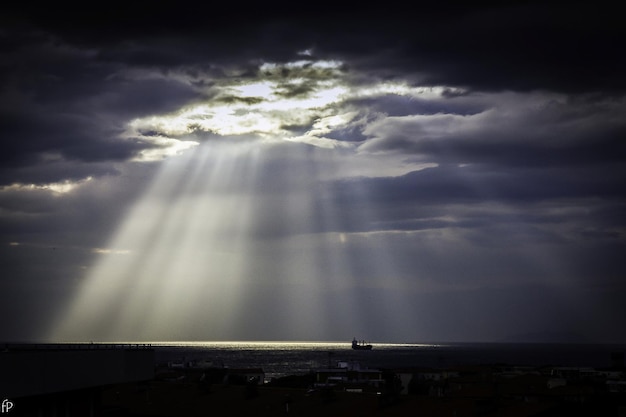 sunlight streaming through storm clouds over sea