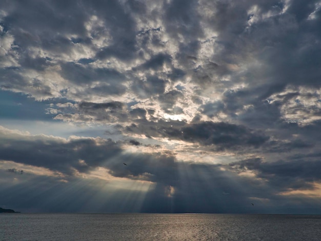 Photo sunlight streaming through storm clouds over sea