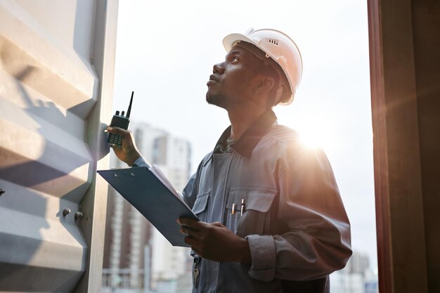 Photo sunlit portrait of young male worker wearing hardhat standing in container door at shipping docks