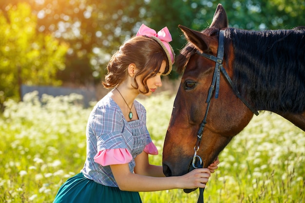 Sunny day beautiful woman standing next to the horse